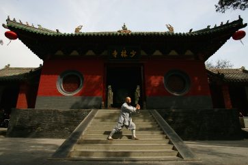DENGFENG, CHINA - APRIL 7: A warrior monk of Shaolin Temple displays his kung fu skills in front of the main gate of the temple April 7, 2005 in Dengfeng, Henan Province, China. Shaolin Temple was built in AD 495 in the period of the Northern and Southern Dynasties (420-581) and located in the Songshan Mountain area, is the birthplace of the Shaolin Kung Fu. Shaolin kung fu, with its incredible strength, vitality and flexibility, is expecting to be included in the UNESCO intangible heritage list. (Photo by Cancan Chu/Getty Images)
